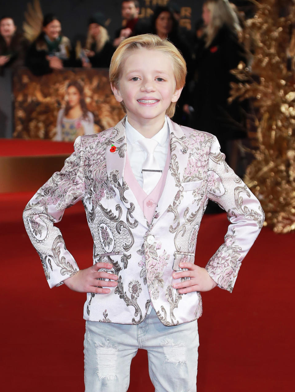 Closeup of Dexter Sol Ansell smiling on the red carpet wearing a vest, a patterned blazer, and jeans