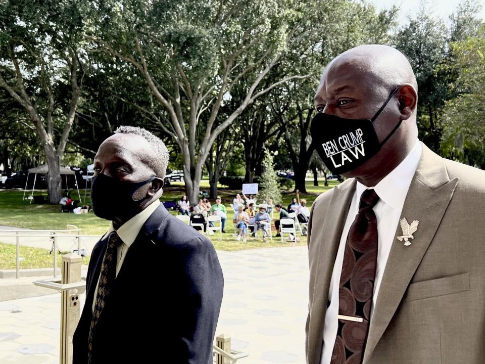 Ahmaud Arbery's father Marcus Arbery, left, heads into the Glynn County Courthouse in Brunswick, Ga with his attorney Benjamin Crump on Monday, Oct. 18, 2021. Jury selection got underway with hundreds of people ordered to report for what could be a long, laborious effort to find jurors to hear the trial of three white men charged with fatally shooting Ahmaud Arbery as he was running in their neighborhood. (AP Photo/Lewis M. Levine)