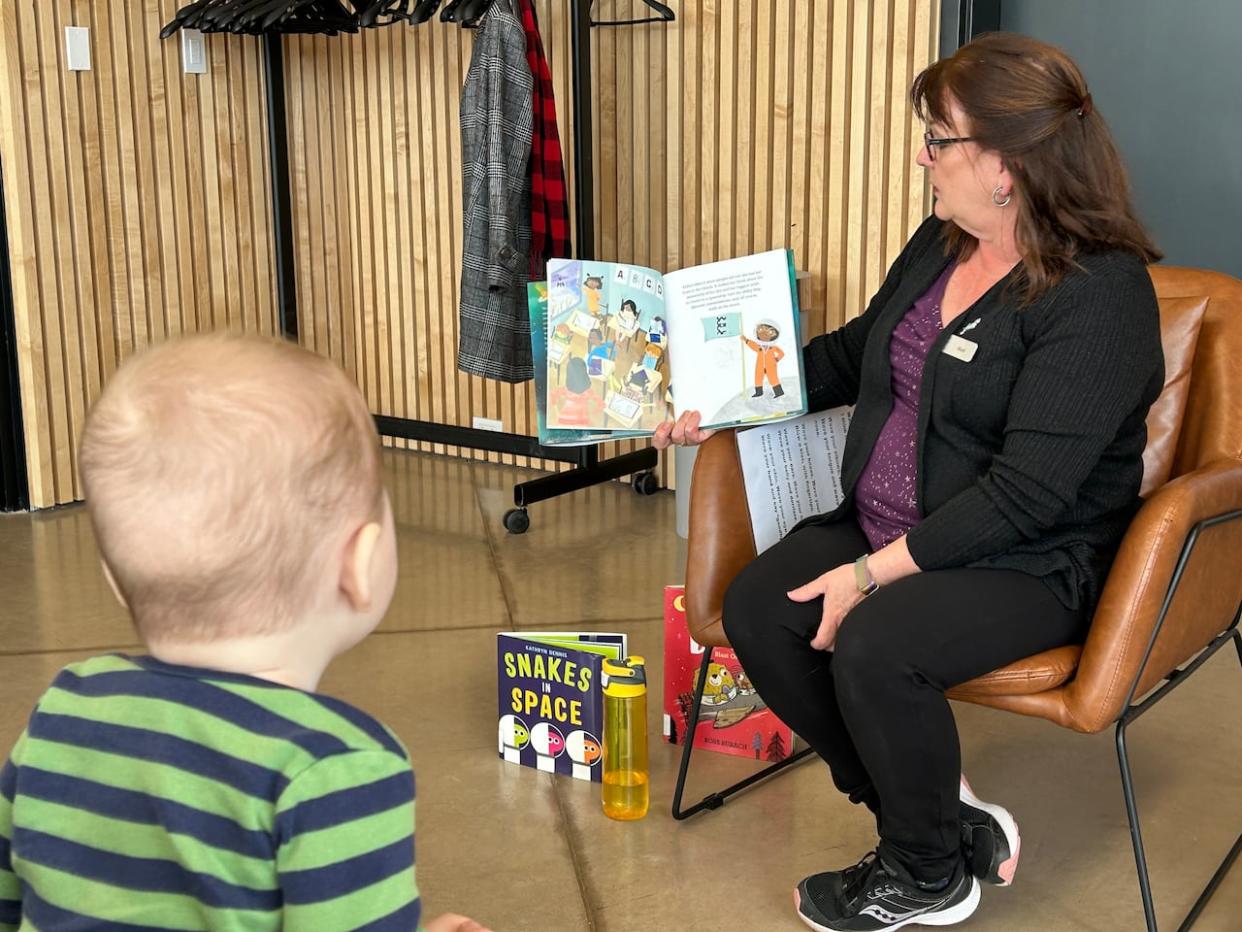 Six-month-old Finneas sits listening on his mother's lap while Hazel Birch reads to the preschool book club in Summerside.  (Stacey Janzer/CBC - image credit)
