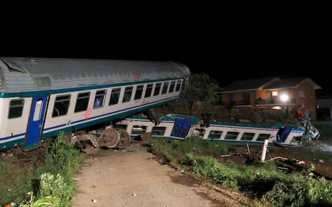 Derailed train cars sit after a regional train plowed into a big-rig truck that stopped on the tracks, in Caluso, outside Turin, Italy - Credit: AP