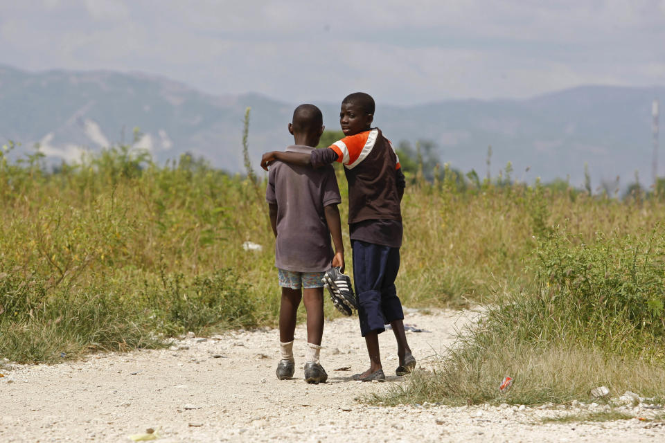 In this May 17, 2012 photo, youths walk together toward a soccer field in the Cite Soleil shantytown where a stadium may be built in Port-au-Prince, Haiti. A local sports hero, a New York real estate developer and a well-known architect are teaming up to build a soccer stadium here, hoping to revive the seaside shantytown. The organizers also hope the stadium, scheduled to break ground within six months and due to be built by the end of 2013, will bring an initial 500 jobs and inject commerce into the shanty city, where politicians to pay residents to fight their battles as proxy forces. (AP Photo/Dieu Nalio Chery)