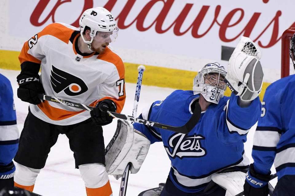 Winnipeg Jets goaltender Connor Hellebuyck (37) makes a glove-save on a shot as Philadelphia Flyers' David Kase (72) looks for the rebound during first-period NHL hockey game action in Winnipeg, Manitoba, Sunday, Dec. 15, 2019. (Fred Greenslade/The Canadian Press via AP)