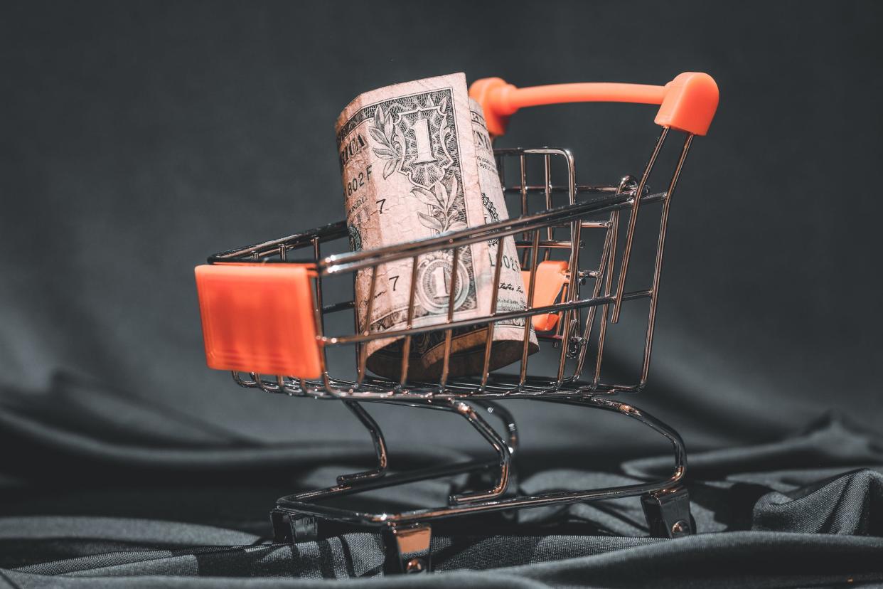 1 USD (United States dollar) placed into supermarket shopping cart. Studio shot isolated on green background illustrating buying power of Americans.