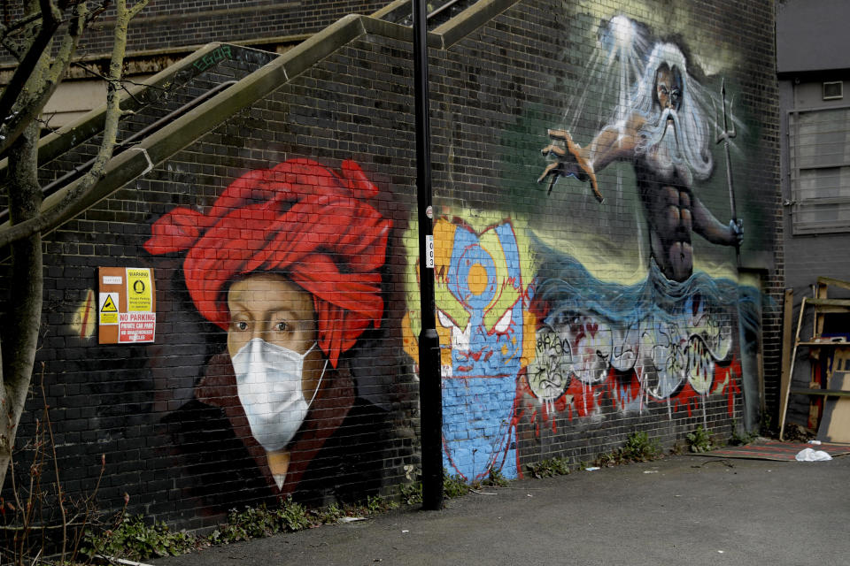 A mural by street artist Lionel Stanhope with a face mask reference to coronavirus next to one of his other works, at right, painted on a bridge wall in Ladywell, south east London, Thursday, April 2, 2020. (AP Photo/Matt Dunham