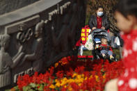 A woman wearing a face mask to help curb the spread of the coronavirus pushes a toddler on a stroller past an Olympics monument at a park in Beijing, Thursday, Nov. 5, 2020. China is suspending entry for most foreign passport holders who reside in Britain, reacting to a new surge of coronavirus cases in the United Kingdom. (AP Photo/Andy Wong)