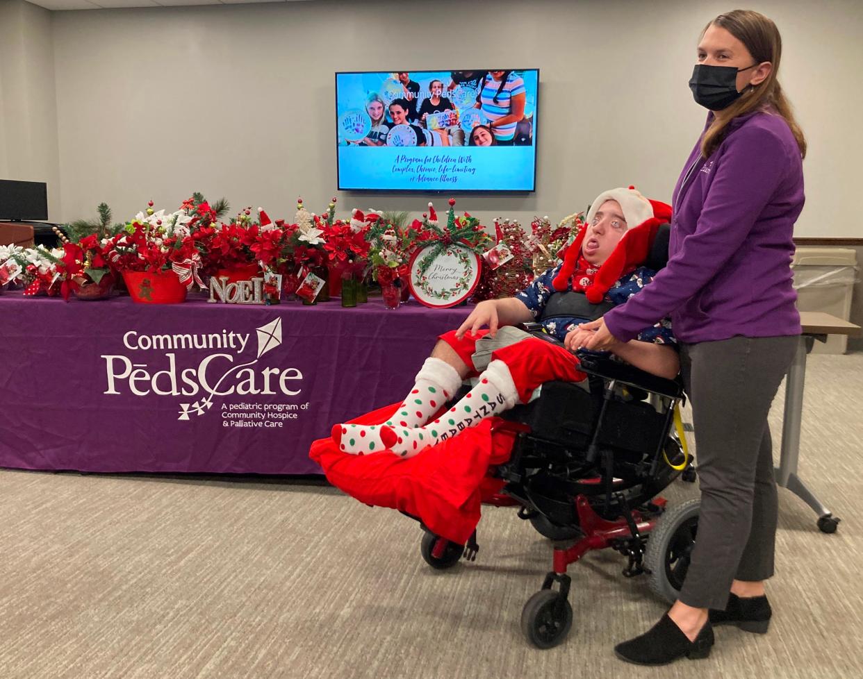 Danielle Eaves, child life specialist with Community PedsCare, stands with William Thompson next to Christmas arrangements that Thompson and his mother made for families in the Community PedsCare program in St. Johns County.