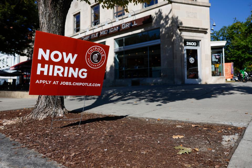 A "Now Hiring" sign is displayed in front of a Chipotle restaurant