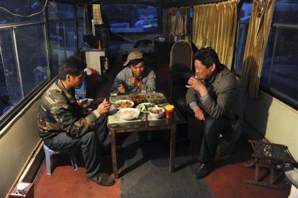 Residents have dinner in a renovated scrapped vehicle which serves as their dwelling, at a dismantling centre for old vehicles on the outskirts of Hefei, Anhui province, China, April 12, 2011. Seven families in the center, with ages from 4 to 84, dismantle old cars as their livelihood during the day and live in renovated scrapped vehicles during the night, local media reported.