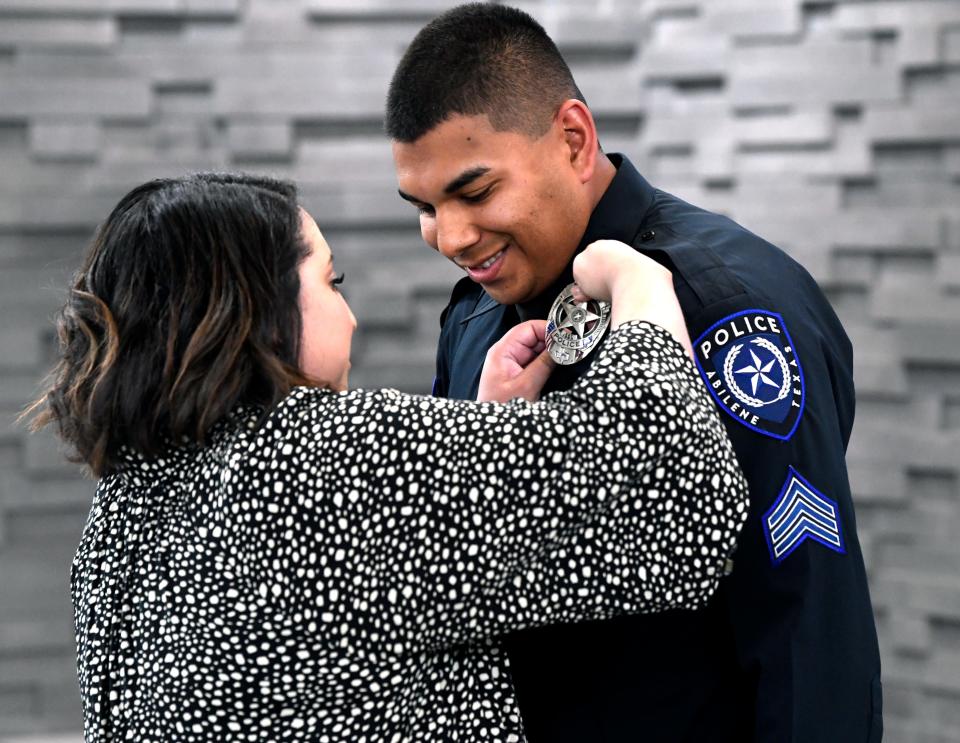 Eddy Hernandez leans forward slightly as his wife Raquel pins his new sergeant’s badge on his uniform at the Abilene Police Department Wednesday.