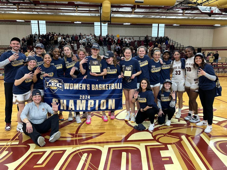The Rhode Island College women's team poses with the banner after winning its fourth straight Little East championship on Saturday.
