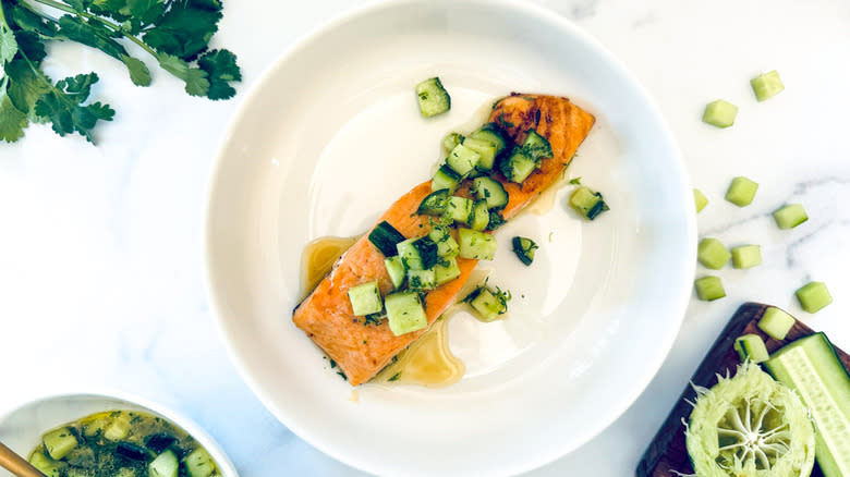 salmon with cucumber topping on white plate