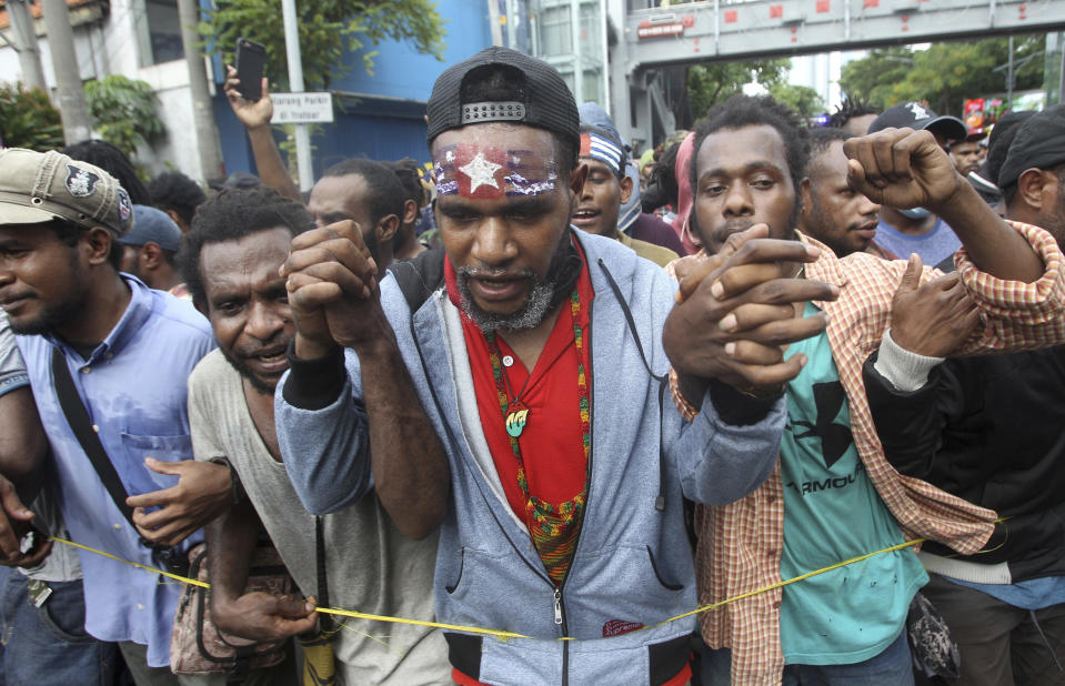 A Papuan activist with his forehead painted with banned separatist flag the "Morning Star" marches with others during a rally commemorating the 57th anniversary of the failed efforts by Papuan tribal chiefs to declare independence from Dutch colonial rule, in Surabaya, East Java, Indonesia, Saturday, Dec. 1, 2018. Indonesia took over West Papua from Dutch colonial rule in 1963 and formalized its sovereignty over the region in 1969 through a vote by about 1,000 community leaders, which critics dismissed as a sham. A separatist group called the "Free Papua Movement" has battled Indonesian rule ever since. (AP Photo/Trisnadi)
