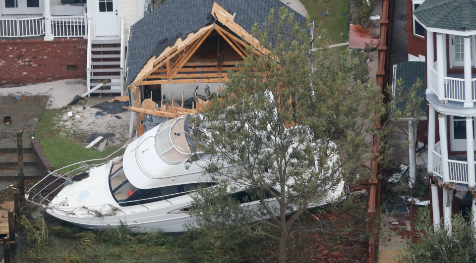 A yacht sits on the Neuse river bank in between buildings after hurricane Florence passed through the area in New Bern, NC., Saturday, Sept. 15, 2018. (AP Photo/Steve Helber)