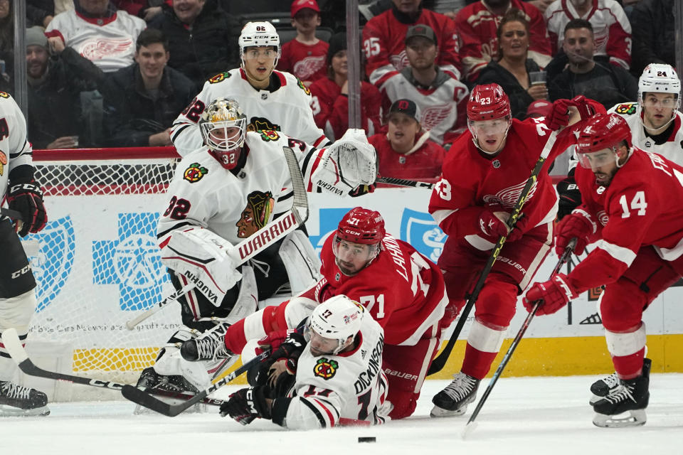 Chicago Blackhawks center Jason Dickinson (17) and Detroit Red Wings center Dylan Larkin (71) hit the ice as they watch the puck in the first period of an NHL hockey game Wednesday, March 8, 2023, in Detroit. (AP Photo/Paul Sancya)