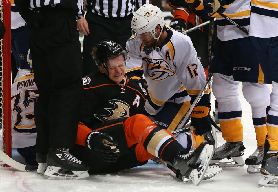 ANAHEIM, CA - APRIL 23: Corey Perry #10 of the Anaheim Ducks winces in pain after a play where he was check hard to the ice into the Predators crease area as Mike Fisher #12 of the Nashville Predators looks on in the first period of Game Five of the Western Conference First Round during the 2016 NHL Stanley Cup Playoffs at Honda Center on April 23, 2016 in Anaheim, California. The Ducks defeated the Predators 5-2.  (Photo by Victor Decolongon/Getty Images)