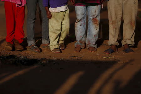 The legs of fruit pickers Genaro Perfecto, 38, and his wife Cecilia Feliciano, 37, are seen as they pose for a photo with their children in the courtyard of their house in San Quintin in Baja California state, Mexico April 1, 2015. REUTERS/Edgard Garrido