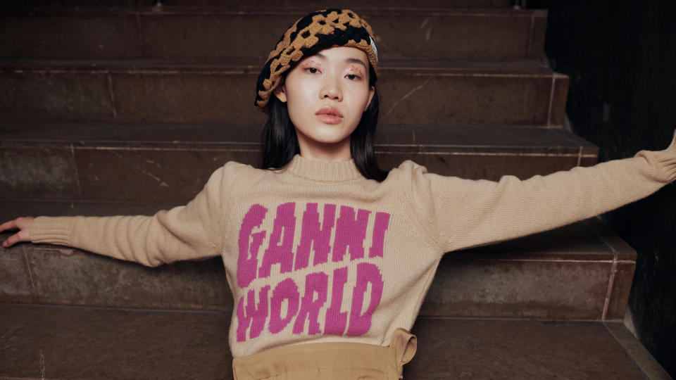 A model's sweater reads "Ganni World" on the steps.