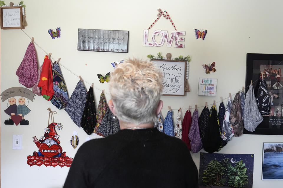 Deb Robertson looks at a wall crafts with her chemo caps at her Lombard, Ill. home, Thursday, March 21, 2024. She didn’t cry when she learned two months ago that the cancerous tumors in her liver were spreading, portending a tormented death. But later, she cried after receiving a call that a bill moving through the Illinois Legislature to allow certain terminally ill patients to end their own lives with a doctor’s help had made progress. (AP Photo/Charles Rex Arbogast)