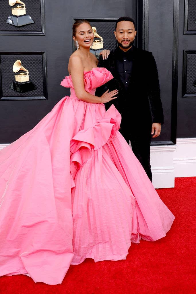 Chrissy smiling in a strapless, frilly gown with her arm on John's shoulder