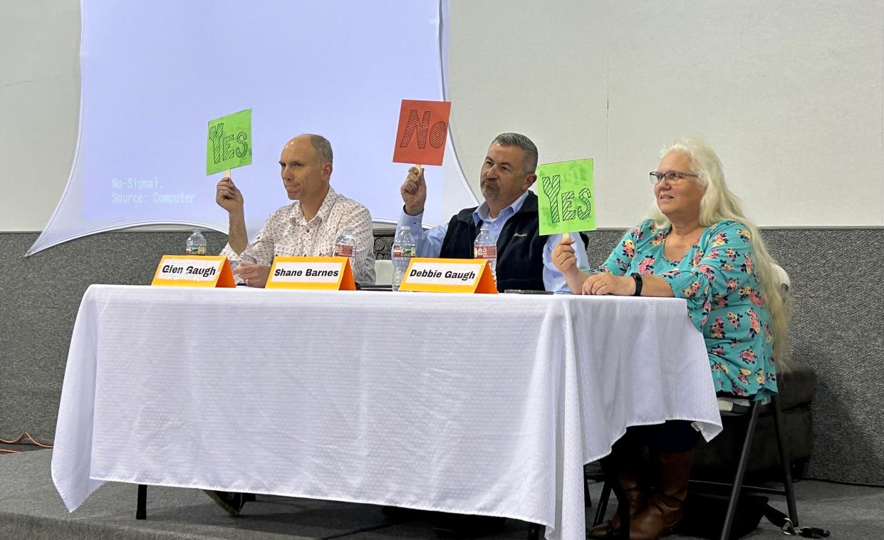 (From left) Glen Gaugh, Shane Barnes, and Debbie Gaugh hold Yes/No signs in response to questions asked at the school board discussion forum on Feb. 20, 2024 at Jackson First Assembly Church in Jackson, Tenn.