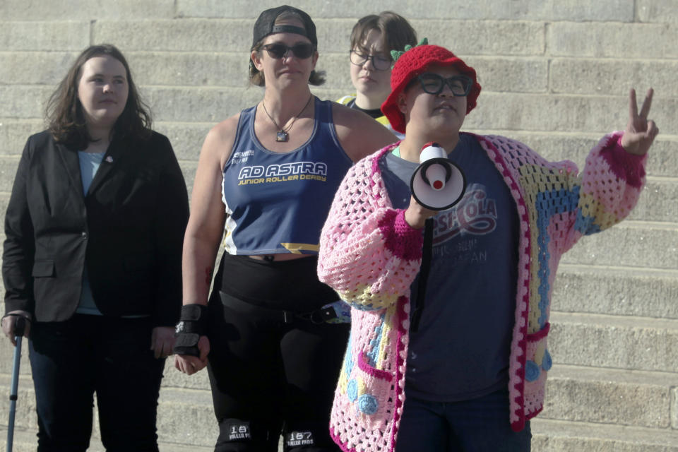 Ian Benalcazar, far right, a 13-year-old transgender boy from Lawrence, Kan., speaks outside the Kansas Statehouse during a rally on Transgender Day of Visibility, Friday, March 31, 2023, in Topeka, Kan. Ian is among more than 100 people, including many transgender youth, who came to the Statehouse to protest bills before Kansas lawmakers that would roll back transgender rights. (AP Photo/John Hanna)