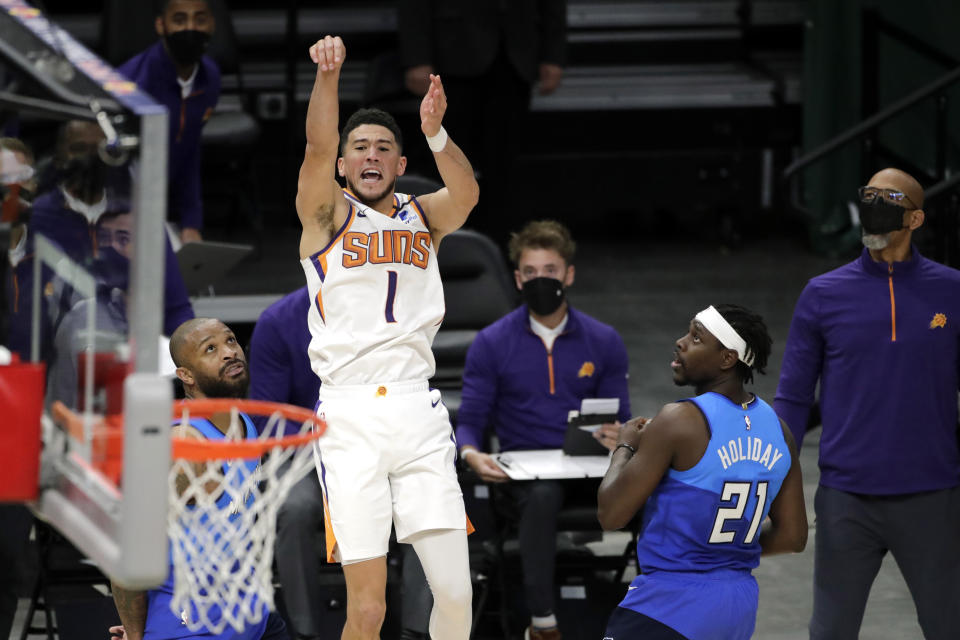 Phoenix Suns' Devin Booker, right, is fouled by Milwaukee Bucks' P.J. Tucker, left, during overtime of an NBA basketball game Monday, April 19, 2021, in Milwaukee. (AP Photo/Aaron Gash)