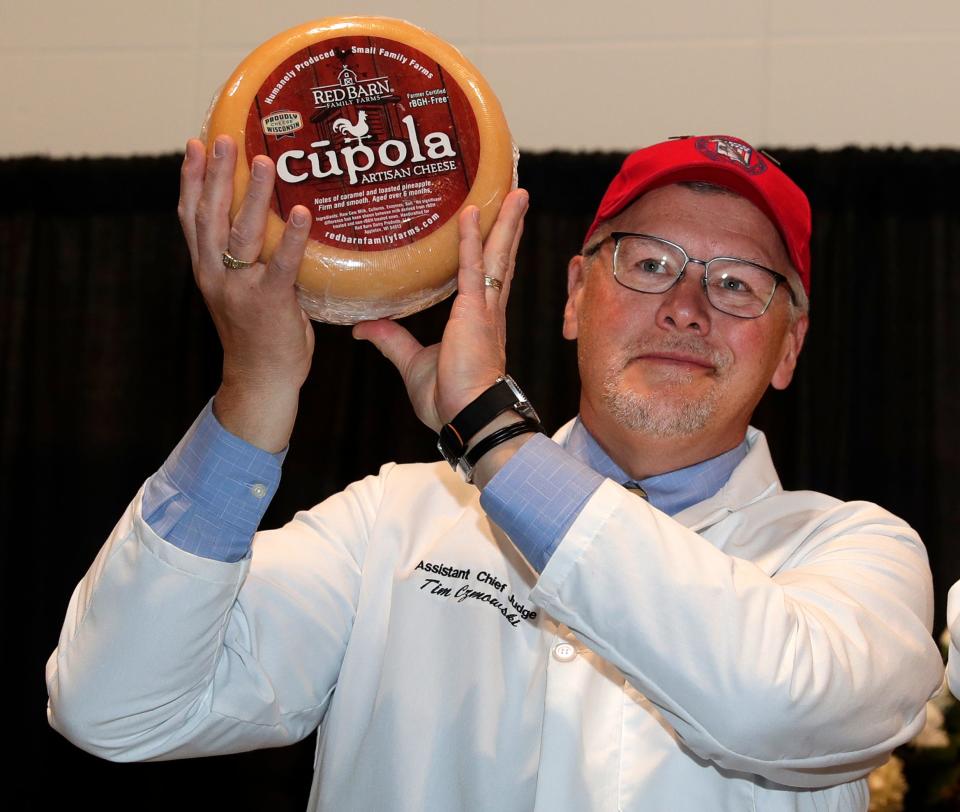 Assistant Chief Judge Tim Czmowski holds up a vintage cupola American original cheese made by Door Artisan Cheese Co. of Egg Harbor for Red Barn Family Farms in Appleton. The cheese took second place overall during the U.S. Championship Cheese Contest on Feb. 23, 2023, at the Resch Expo in Ashwaubenon.