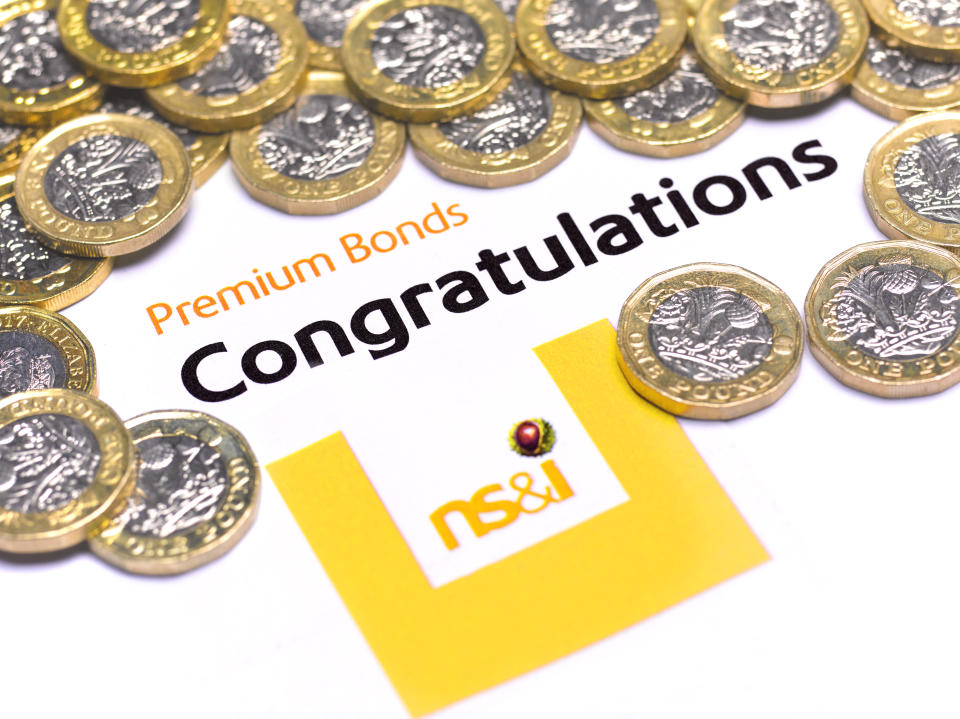 A Premium Bond congratulatory note and pound coins. Premium Bonds are a lottery bond issued by the government's National Savings and Investments (NS&I) agency