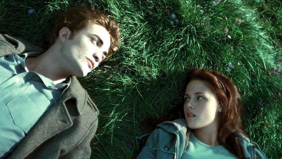 Robert Pattinson and Kristen Stewart lie in grass in vampire renaissance film Twilight.