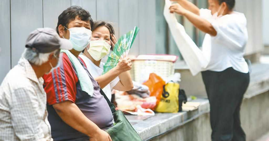 全台氣溫飆升，27日各地出現30度以上高溫，昨用電飆破歷史紀錄，創下新高，中午有民眾坐在路旁搧風納涼。（圖／中國時報鄧博仁攝）