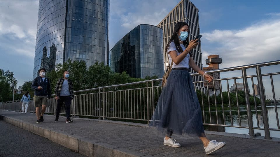 People wear protective masks as they walk across a bridge over the Liangma River on May 24 in Beijing. - Kevin Frayer/Getty Images