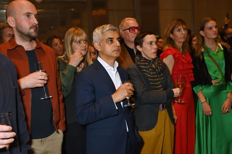 Mayor of London Sadiq Khan holding a drink whilst standing with other people