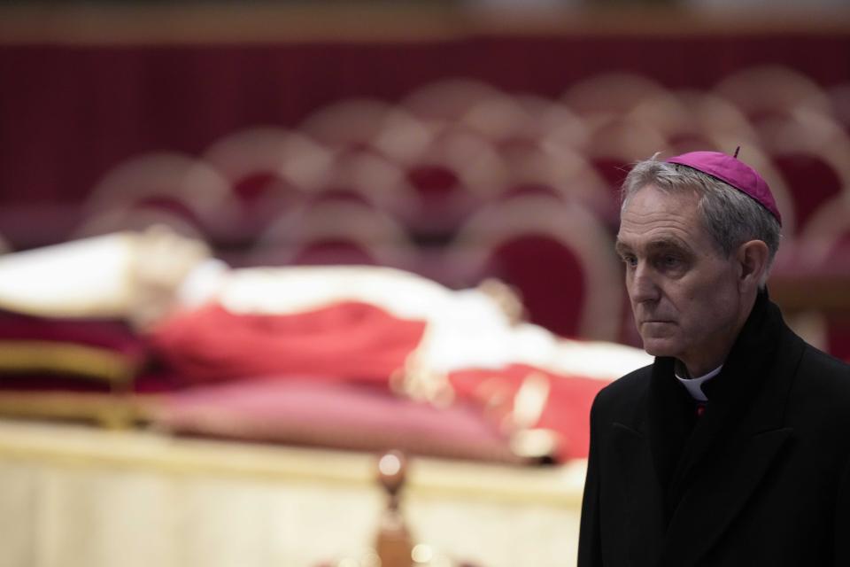 The body of late Pope Emeritus Benedict XVI laid out in state as father Georg Gaenswein stands on the right inside St. Peter's Basilica at The Vatican, Monday, Jan. 2, 2023. Benedict XVI, the German theologian who will be remembered as the first pope in 600 years to resign, has died, the Vatican announced Saturday. He was 95. (AP Photo/Andrew Medichini)