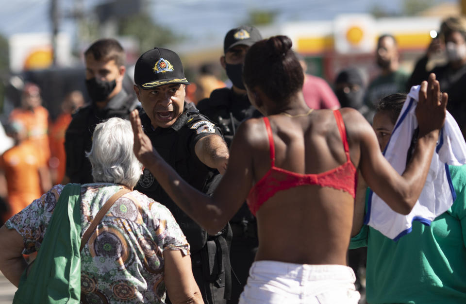 A squatter argues with a police officer during an eviction at a settlement coined the "First of May Refugee Camp," named for the date people moved on the land designated for a Petrobras refinery, in Itaguai, Rio de Janeiro state, Brazil, Thursday, July 1, 2021, amid the new coronavirus pandemic. (AP Photo/Silvia Izquierdo)