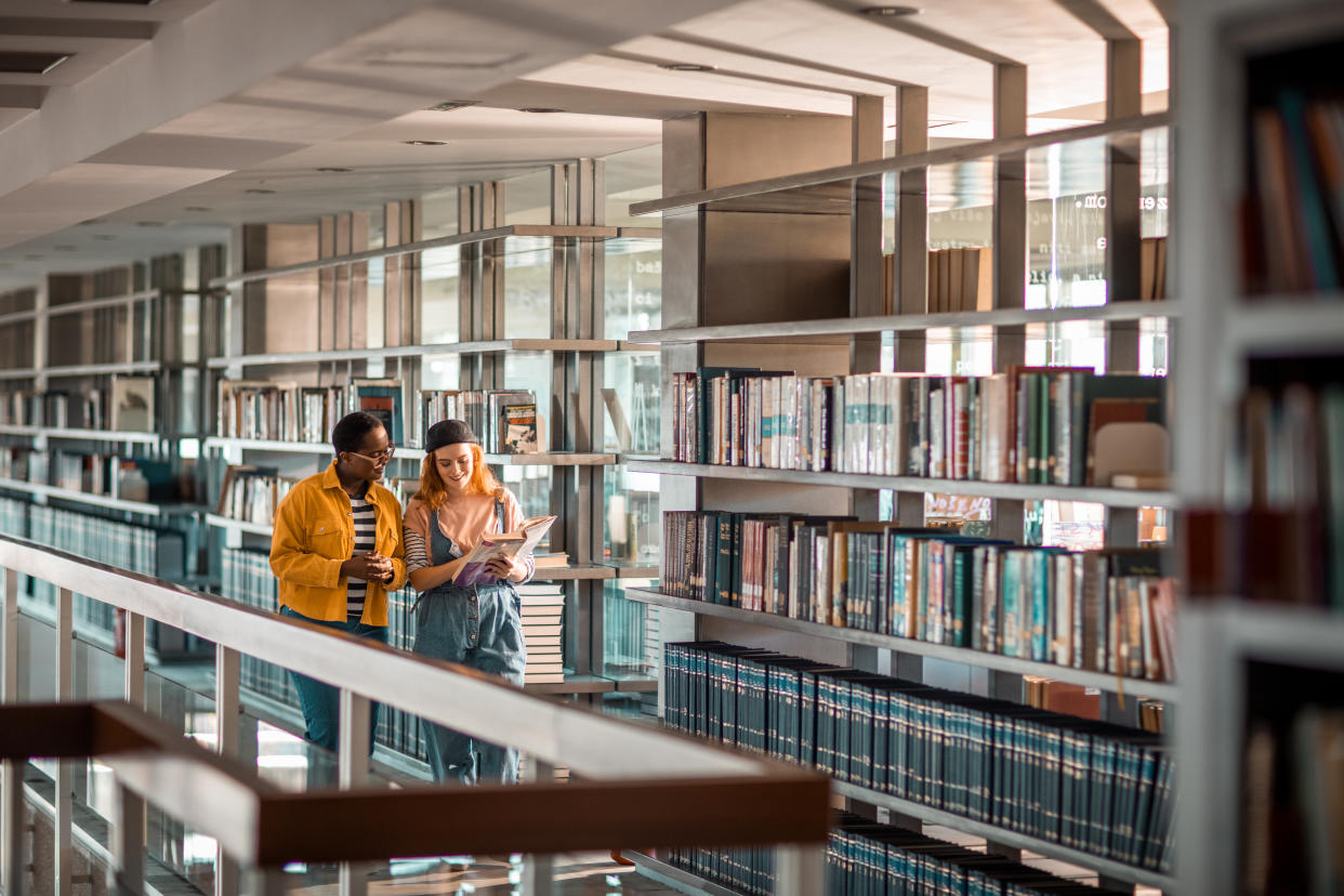 Close up of two female students talking about a book in the library