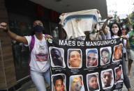 Mothers, who said their sons were killed during police operations, holds a banner with the photos of their sons, during a protest against crimes committed by the police against black people in the favelas, Rio de Janeiro, Brazil, Sunday, May 31, 2020. The protest, called "Black lives matter," was interrupted when police used tear gas to disperse people. "I can't breathe", said some of the demonstrators, alluding to the George Floyd's death. (AP Photo/Silvia Izquierdo)