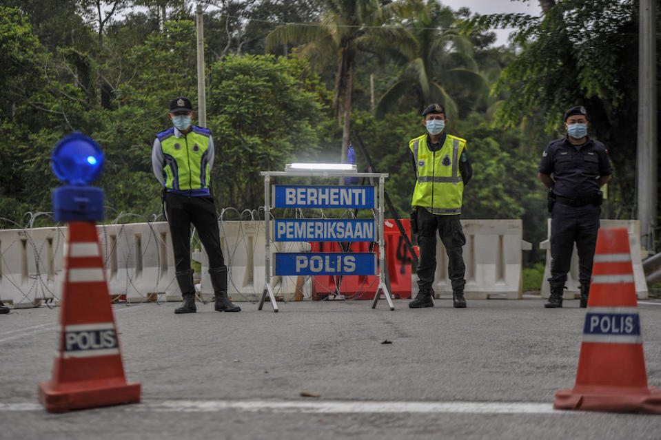 Police officers conducting checks at a roadblock during the enhanced movement control order (EMCO) in seven villages in Hulu Langat, March 30, 2020. — Picture by Shafwan Zaidon