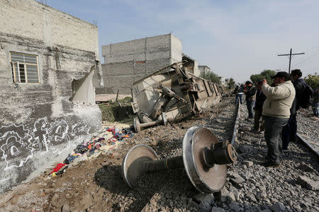 A man takes pictures of the car of a cargo train that ran off the tracks knocking a home in the municipality of Ecatepec, on the outskirts of Mexico City, Mexico January 18, 2018. REUTERS/Daniel Becerril