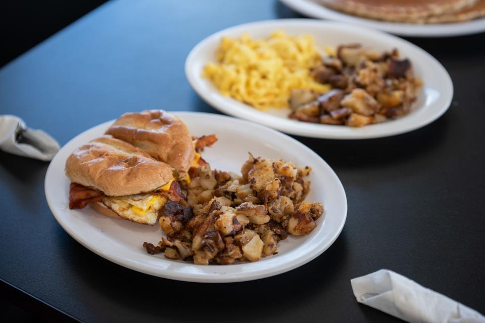 A bacon, egg and cheese on a kaiser roll, served with home fries, at Over EZ's Cafe in Lake Worth Beach.