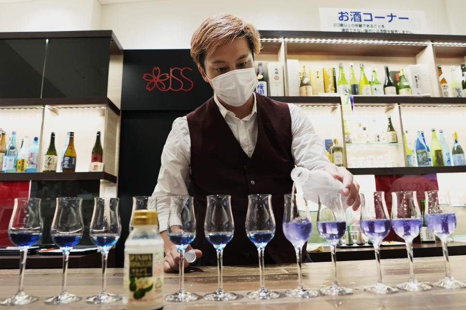 Yusuke Koike, manager for the overseas operation division of the Japan Sake and Shochu Makers Association (JSS), prepares alcohol beverage during a sake and shochu tasting event at JSS Information Center in Tokyo, Wednesday, June 22, 2022. Shuso Imada, general manager at the JSS Information Center, a sake and shochu showroom in downtown Tokyo, said he has been feeling pretty lonely and is itching to tell foreign visitors about how to match the traditional Japanese rice wine with all kinds of non-Japanese food, even cheese and beef. (AP Photo/Hiro Komae)