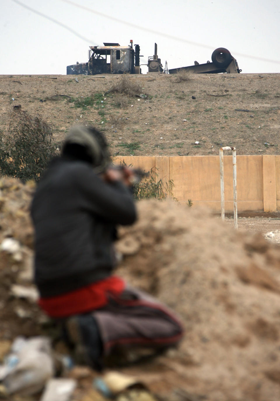 A burned army truck looks over a hill as a gunman guards after clashes with Iraqi security forces on the outskirts of Fallujah, 40 miles (65 kilometers) west of Baghdad, Iraq, Sunday, Jan. 5, 2014. Lt. Gen. Rasheed Fleih, who leads the Anbar Military Command, told the state television Sunday that "two to three days" are needed to push the militants out of Fallujah and parts of Ramadi. (AP Photo)