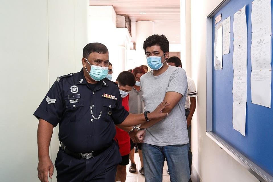 Muhammad Aslam Hashim is escorted by a policeman at the Magistrate’s Court in George Town April 23, 2021. ― Picture by Sayuti Zainudin