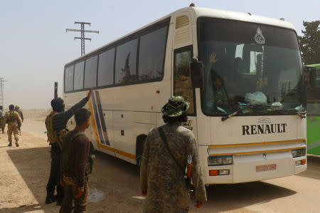 Rebel fighters welcome a convoy of buses carrying Sunni rebels and civilians, who were evacuated from Zabadani and Madaya, as part of a reciprocal evacuation deal for four besieged towns, upon their arrival at al-Rashideen to travel later towards rebel-held Idlib, Syria April 21, 2017. REUTERS/Ammar Abdullah