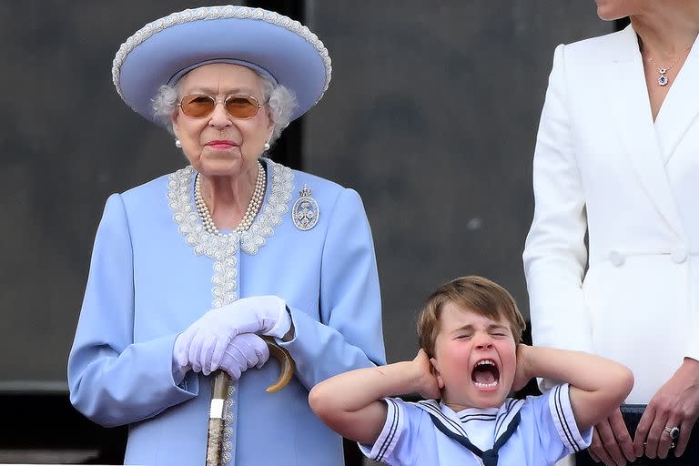 El príncipe Luis de Cambridge de Gran Bretaña se tapa las orejas mientras está de pie junto a la reina Isabel II de Gran Bretaña para ver un vuelo especial desde el balcón del Palacio de Buckingham