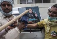 Supporters of Tahir ul-Qadri, a Sufi cleric and leader of Pakistan Awami Tehreek (PAT) party, use a sandal to hit a defaced portrait of Prime Minister Nawaz Sharif, as a sign of disrespect, after storming the building of the state television channel PTV, during the Revolution March in Islamabad September 1, 2014. REUTERS/Zohra Bensemra