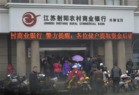 People gather in front of a branch of Jiangsu Sheyang Rural Commercial Bank, in Yancheng, Jiangsu province, March 25, 2014. REUTERS/Stringer