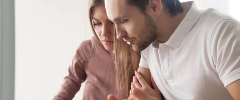 Serious couple studying contract agreement, reading terms and conditions attentively before signing