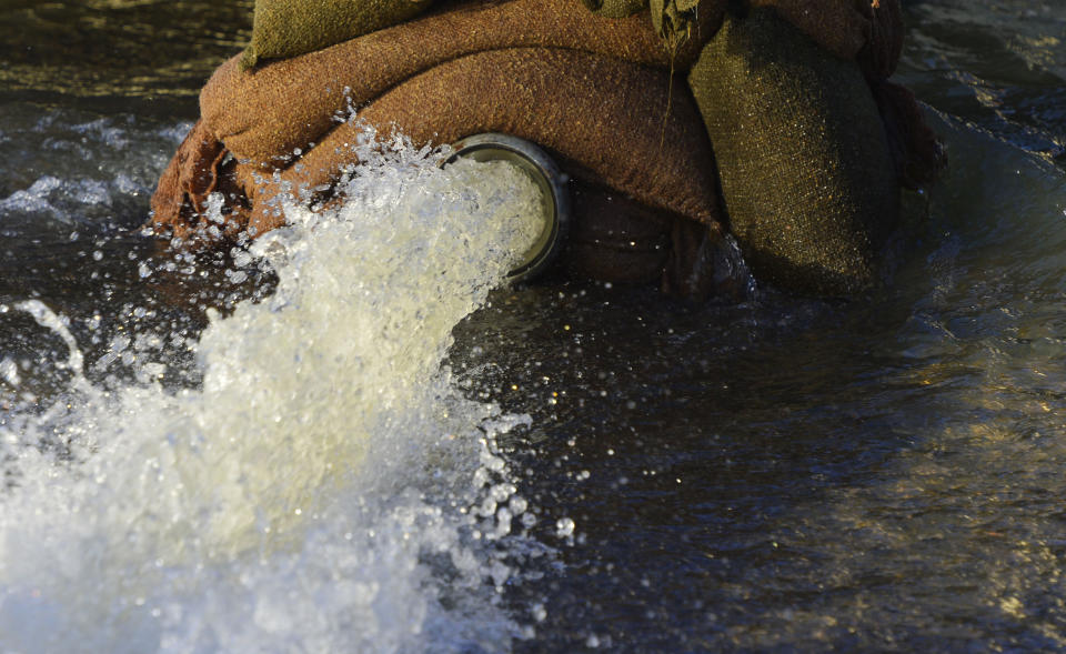 Water is pumped out of a flooded property in Chertsey in southern England