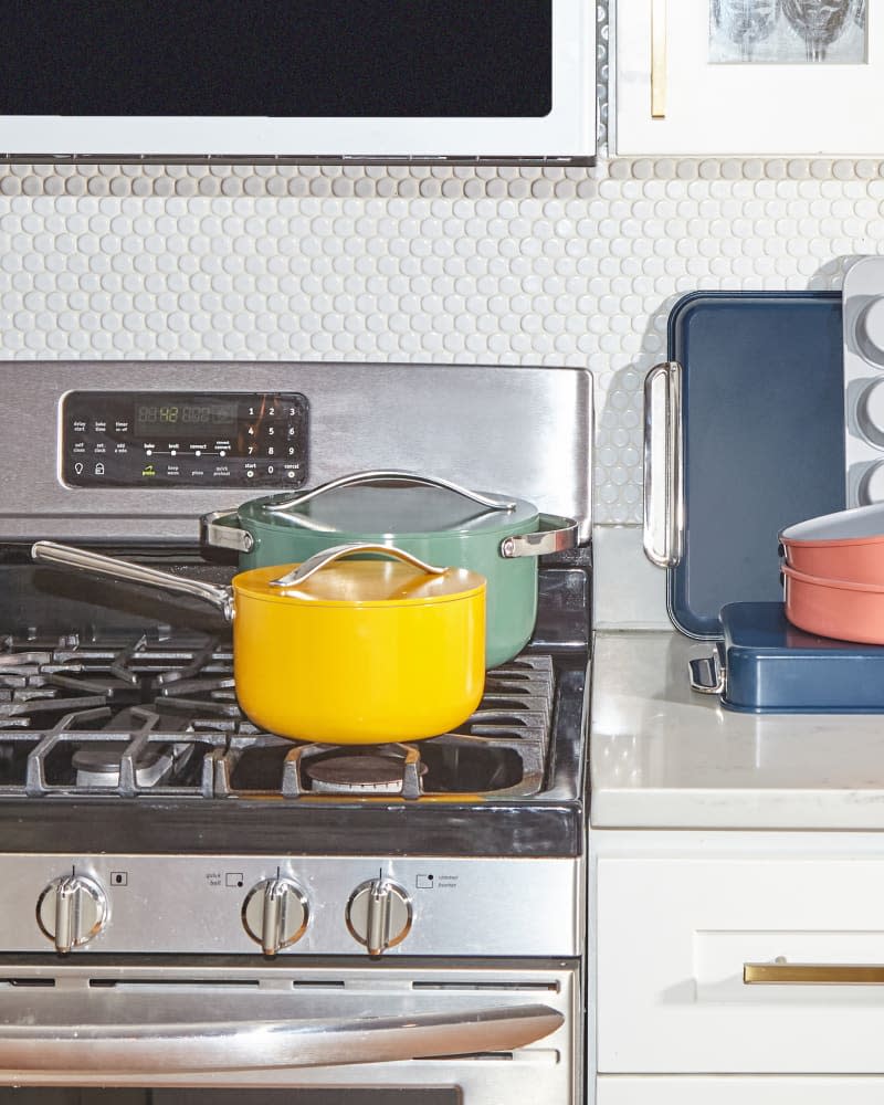 Caraway Home cookware pots in sage and marigold colors on stovetop