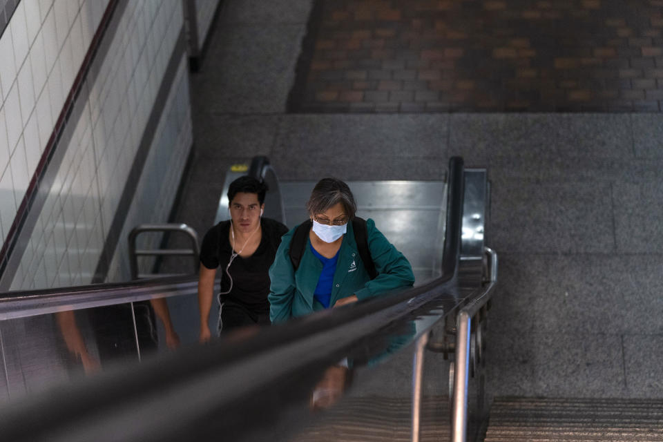 Two commuters ride an escalator as they exit a Metro station in Los Angeles, Wednesday, July 13, 2022. Los Angeles County, the nation's largest by population, is facing a return to a broad indoor mask mandate if current trends in hospital admissions continue, health director Barbara Ferrer told county supervisors Tuesday. (AP Photo/Jae C. Hong)